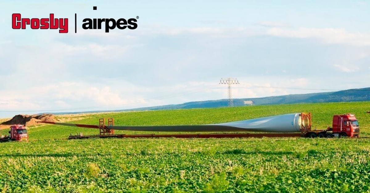 Picture of a red truck transporting a wind mill blade to a wind farm