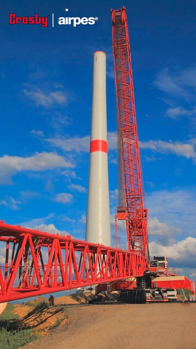 Red crane building the tower of a wind turbine