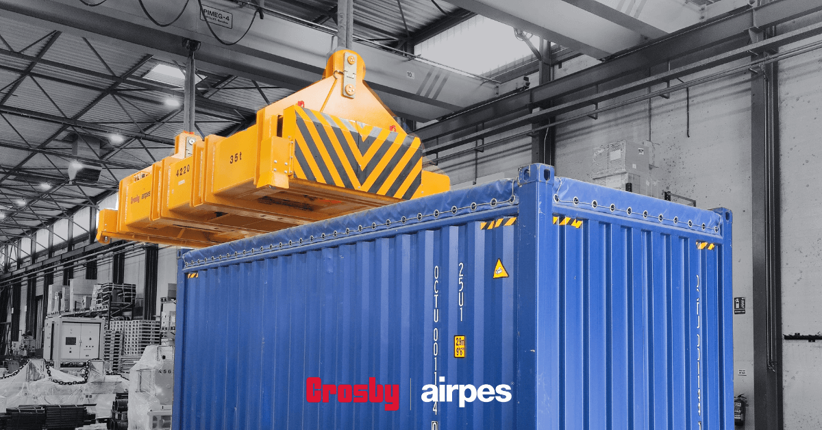 Hydraulic lifting spreader beam by Crosby Airpes lifting a 40-foot container with twist lock system and status lights in port environment.