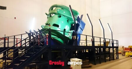 Industrial load turning device installed in a manufacturing facility, designed for controlled rotation and safe positioning of heavy industrial components during handling and assembly operations.