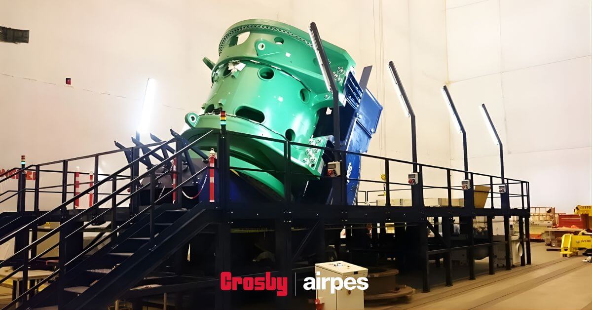 Industrial load turning device installed in a manufacturing facility, designed for controlled rotation and safe positioning of heavy industrial components during handling and assembly operations.