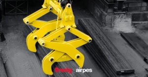 Yellow scissors lifting tong handling steel material in an industrial plant by Crosby Airpes